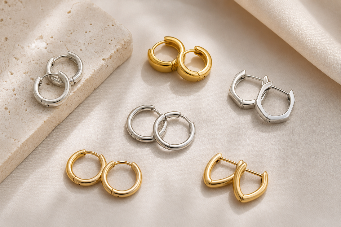 Small silver and gold hoop earrings arranged on a neutral surface