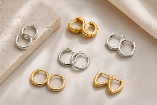 Small silver and gold hoop earrings arranged on a neutral surface