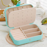 Leather travel jewelry box with button closure and compartments for rings, earrings, and bracelets